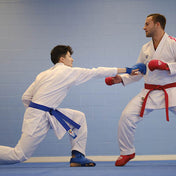Blue and red competition belts tied on white martial arts gi uniforms