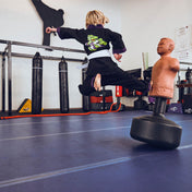 Child wearing black martial arts gi with green dragon back graphic and purple trim