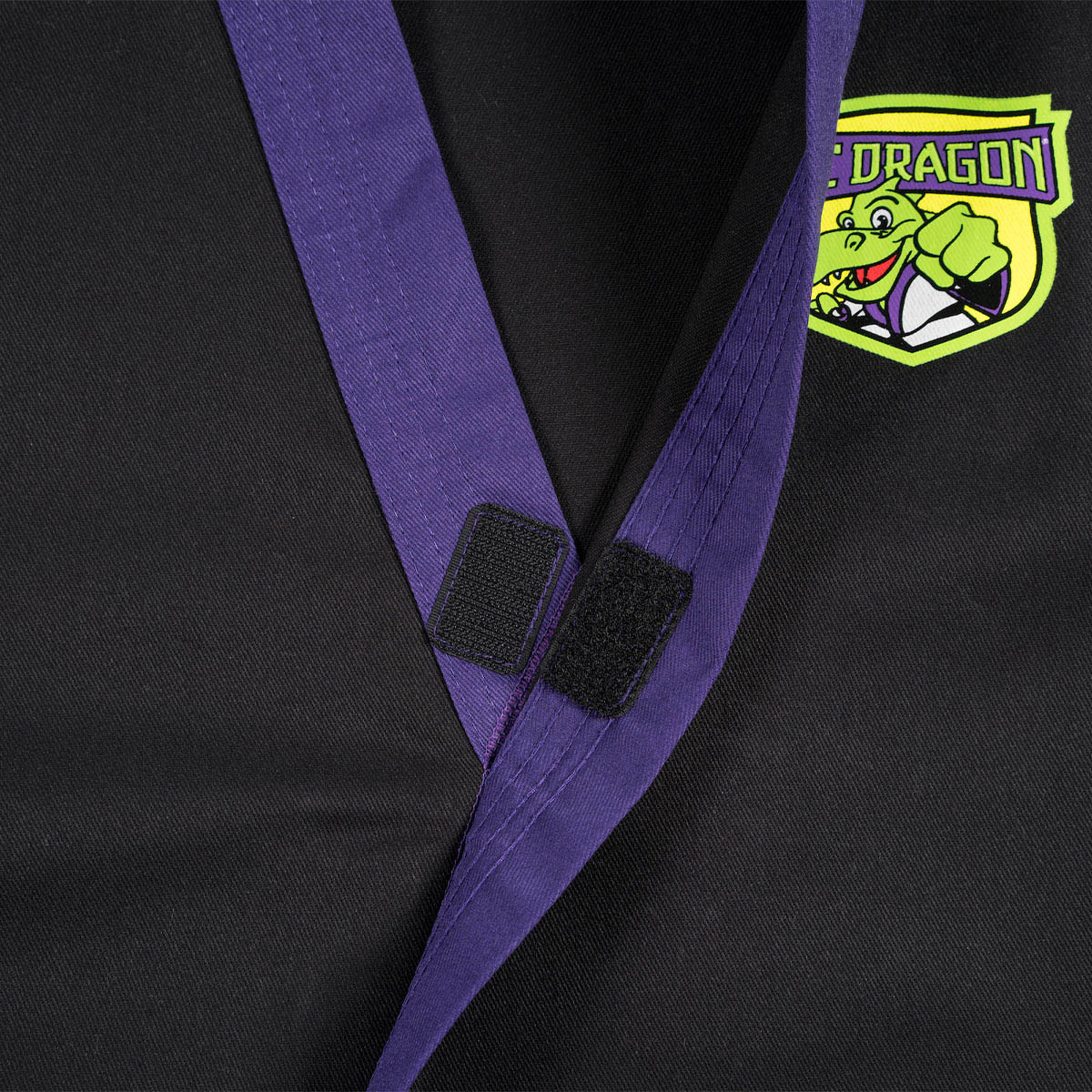 Black martial arts gi collar detail with purple trim and dragon emblem patch