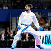 White karate gi with blue belt, athlete in sparring stance with gloves.