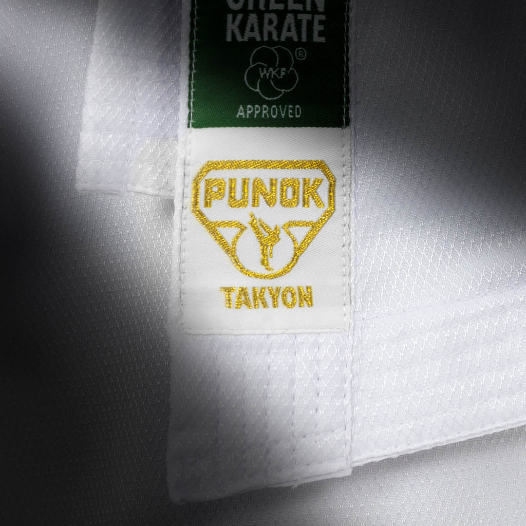 Close-up of karate gi label: green top tag and “PUNOK” patch with gold text.