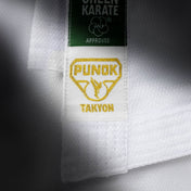 Close-up of karate gi label: green top tag and “PUNOK” patch with gold text.