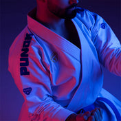 Martial arts gi jacket with woven logo on sleeve, worn with belt and pants
