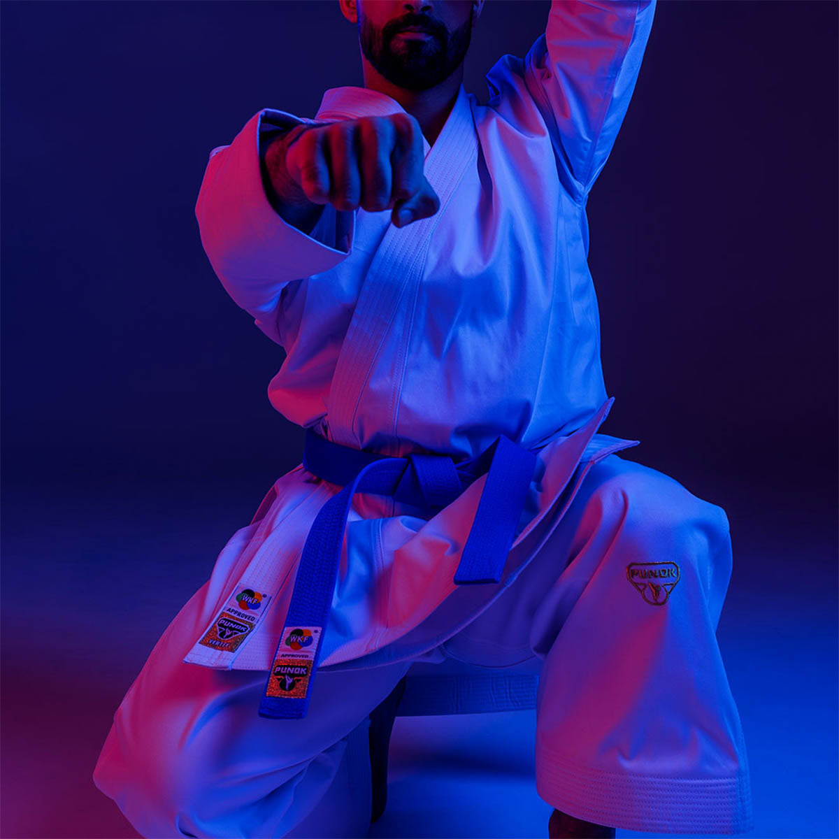 Martial arts gi set worn in a seated stance, jacket and pants with belt