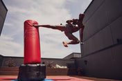 Red inflatable punching bag on a black base, outdoor training setup