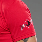 Red unisex t-shirt sleeve with small logo graphic, close-up