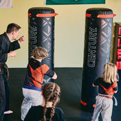 Black freestanding boxing bags with red straps and Century logo panels