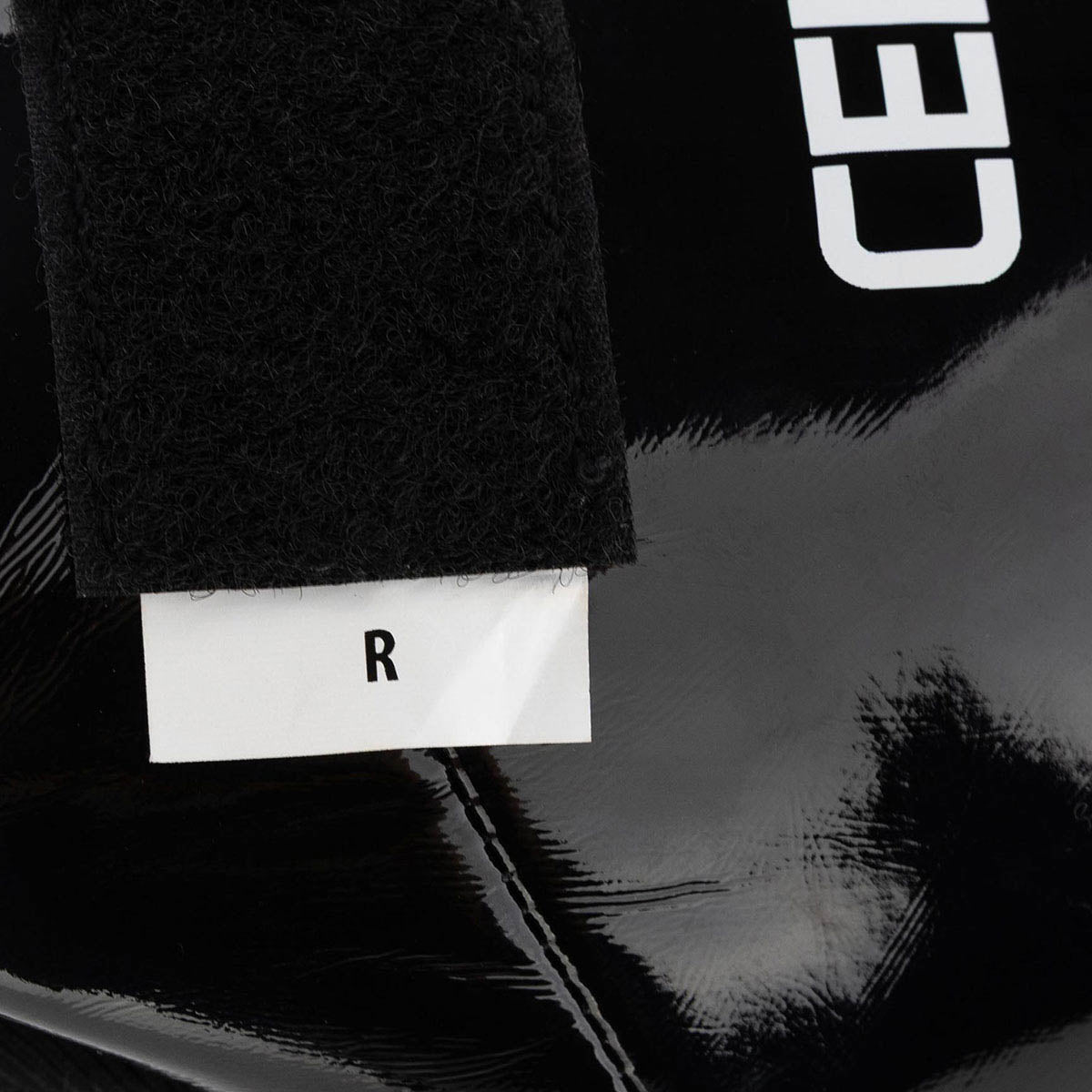 Black boxing kick boot with white label patch and glossy protective front panel