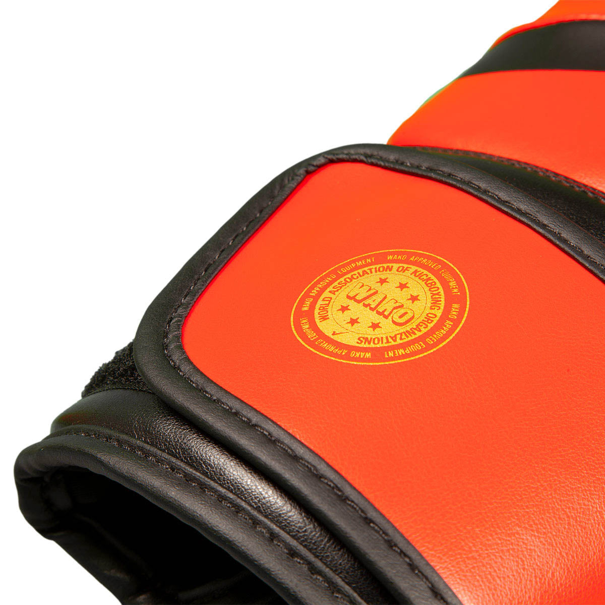 Red kickboxing gloves close-up with round logo patch and black stitched knuckle padding