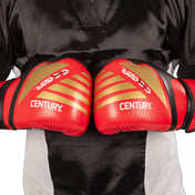 Red kickboxing gloves with gold diagonal stripes and Century branding, pair close-up