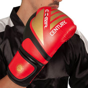 Red and black kickboxing glove with gold panel, Century logo, curved wrist strap