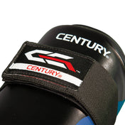 Close-up of black shin guard branding patch with Century logo on padded surface.
