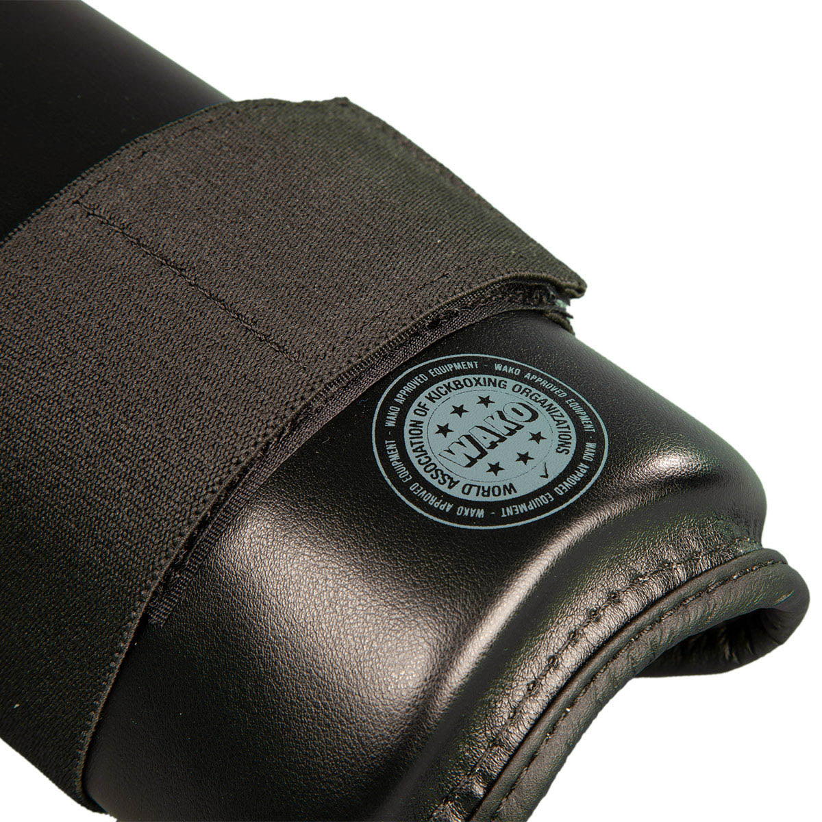 Black shin guard with circular stamp on padded knee/shin area and fabric edge stitching.