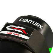 Close-up of black shin guard with Century branding patch and red/white logo graphic.