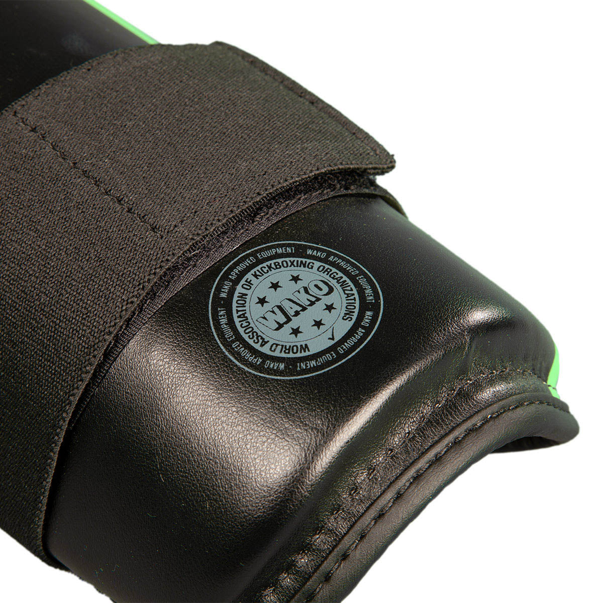 Close-up of black shin guard with circular stamp on padded surface and stitched fabric edge.