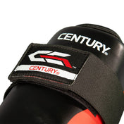 Close-up of black boxing shin guard with CENTURY logo patch and red accent stripe