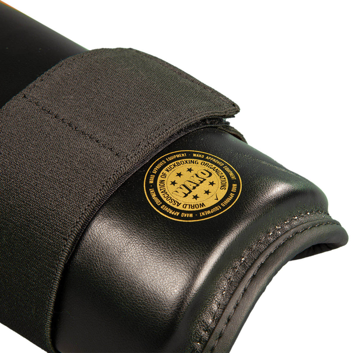 Close-up of black boxing shin guard end pad with round yellow certification patch
