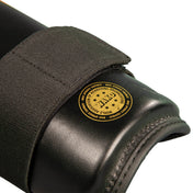 Close-up of black boxing shin guard end pad with round yellow certification patch
