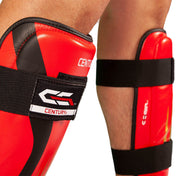 Red shin guard close-up with Century logo patch and black hook-and-loop straps