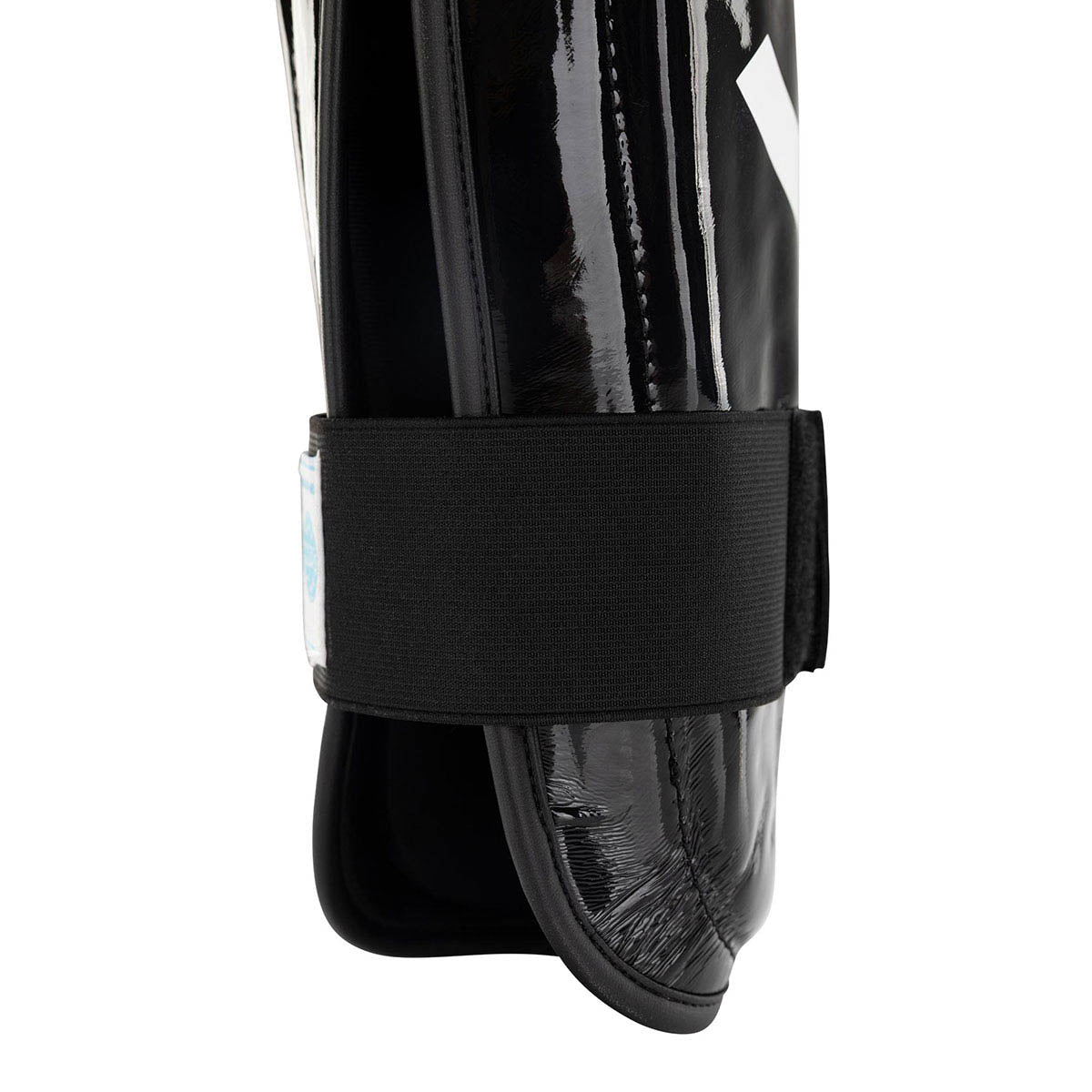 Black shin guards with wide fabric strap and glossy shell, side close-up
