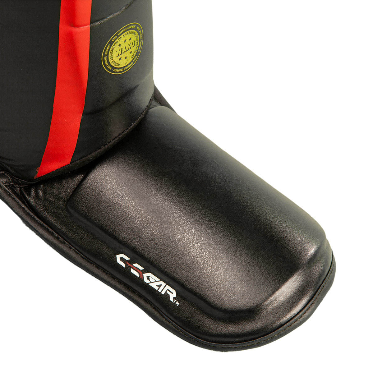 Black leather shin instep guard with red panel and yellow emblem near the ankle