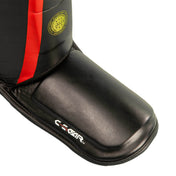 Black leather shin instep guard with red panel and yellow emblem near the ankle
