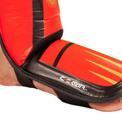 Red shin-instep guard close-up with black ankle strap and molded padding
