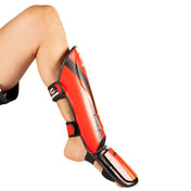 Red and black shin-instep guards worn, showing curved instep and ankle strap