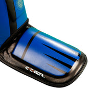 Blue and black shin-instep guard close-up with graphic stripes and padded edge