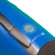Blue shin-instep guard close-up with circular logo patch and gray strap