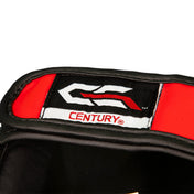 Red and black shin guard strap detail with Century label on white panel