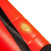 Red shin guard with gold seal logo and black center strap