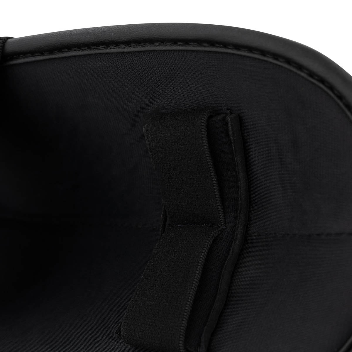 Black fabric upper close-up with stitched seam panel and small pull-tab detail