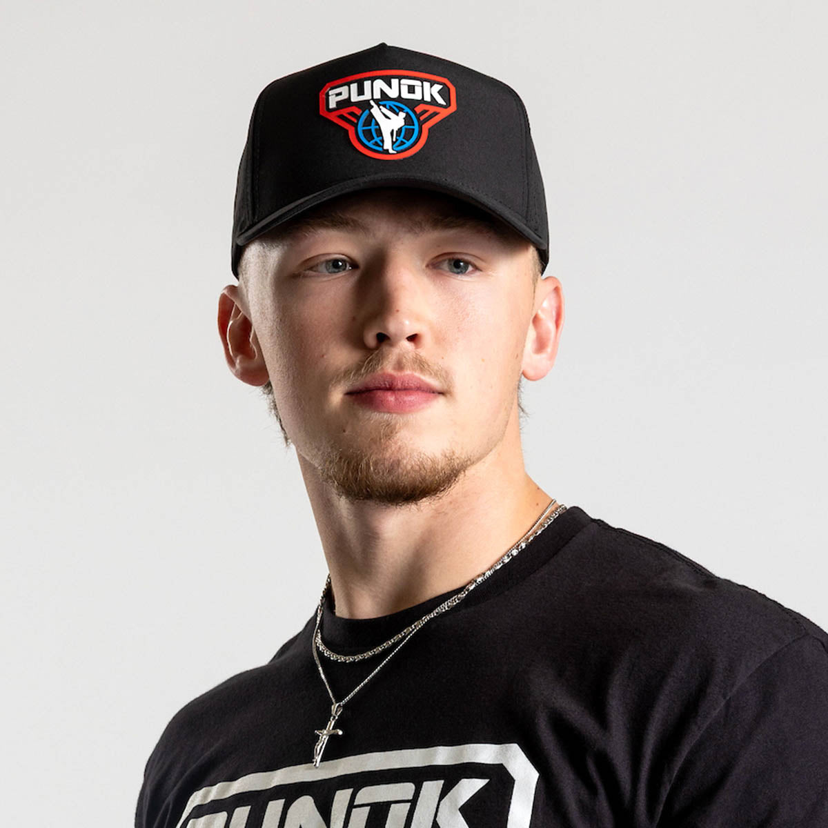 Black performance fighter hat worn by a person, featuring the PUNOK front logo.