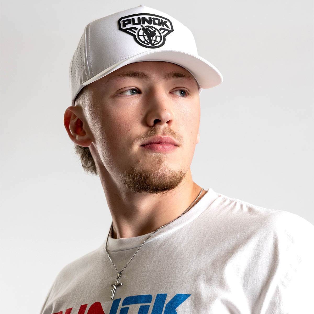 White performance fighter hat worn by a person, featuring the PUNOK front logo.