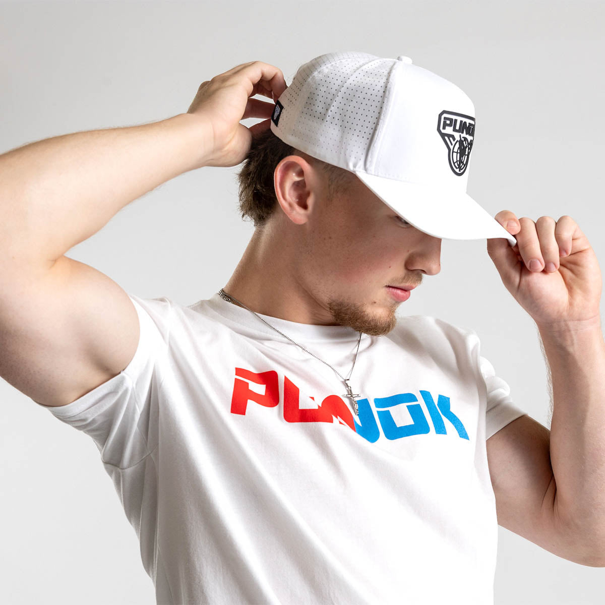 White performance fighter hat being adjusted with PUNOK logo on the front.