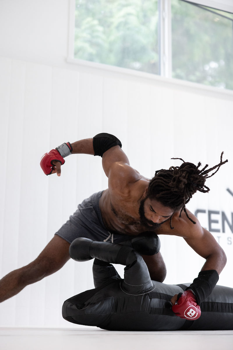 Black grappling dummy with rounded head, padded arms, and Century branding during grappling practice.