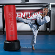 Red Century punching bag with black base, in-use during high kick training