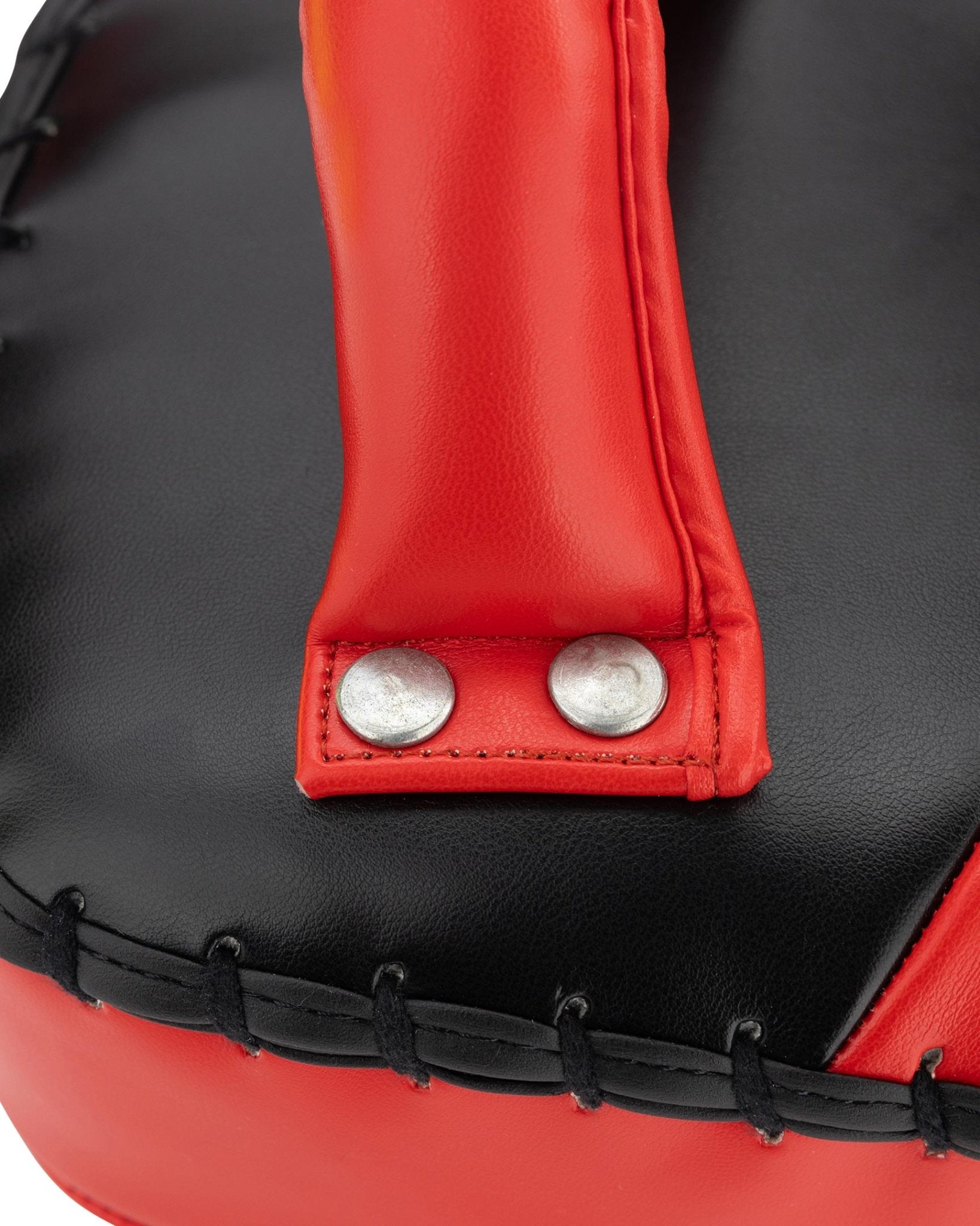 Close-up of red and black Muay Thai pad with metal snap closure and stitched strap
