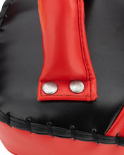 Close-up of red and black Muay Thai pad with metal snap closure and stitched strap