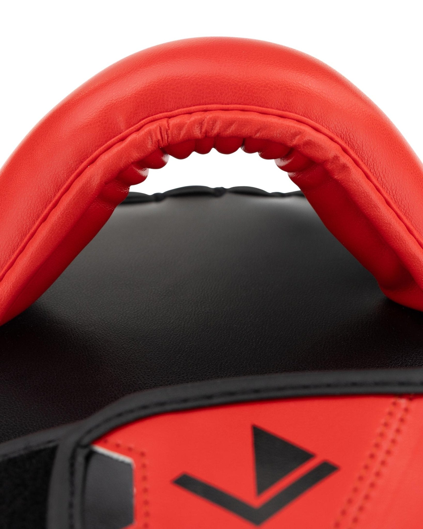Close-up of red and black curved Muay Thai pad with stitched top edge padding
