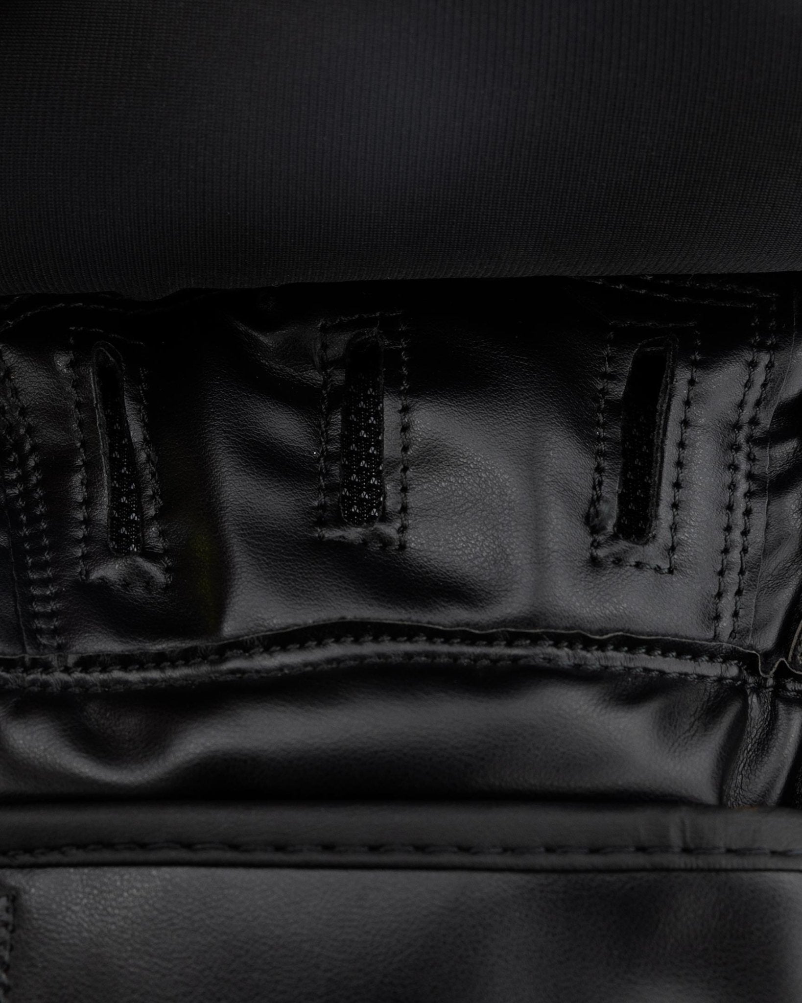Close-up of black leather palm panel and reinforced seams on focus mitt