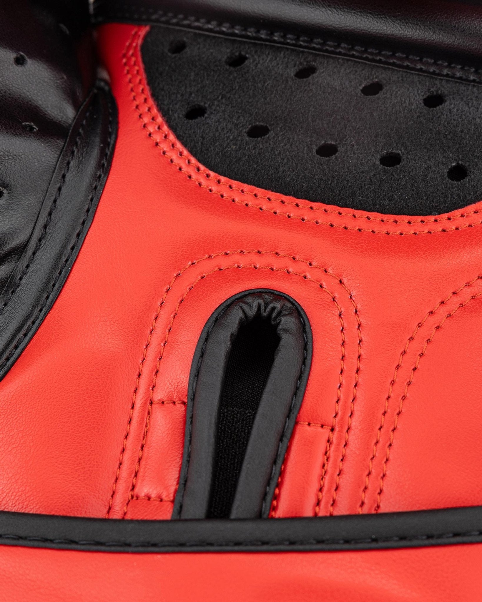 Close-up red heavy bag glove with central knuckle protector and perforations