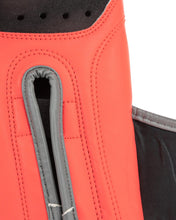 Heavy bag boxing glove close-up: red finger panel with vent holes and grey strap opening