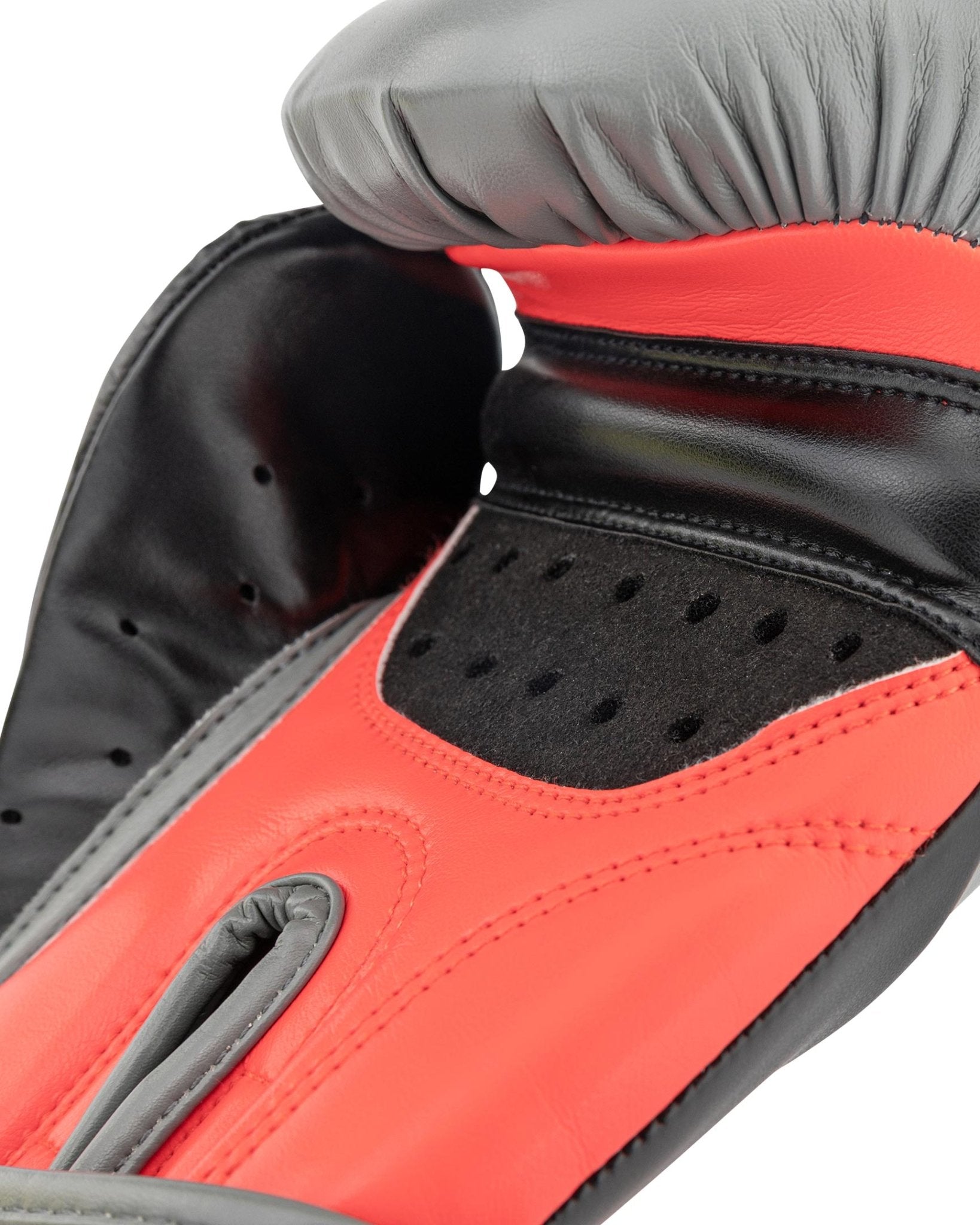 Heavy bag boxing glove close-up: black-and-red palm with vent holes and padded thumb area