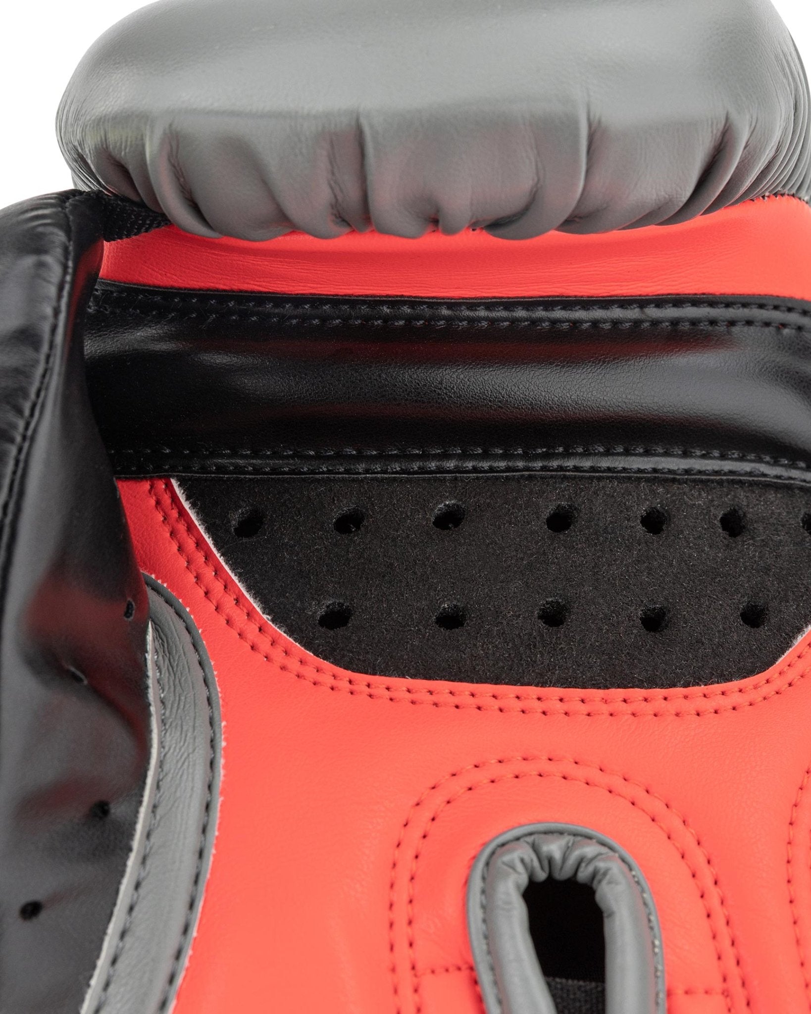 Heavy bag boxing glove close-up: black upper with red underside, stitched seams, and vented palm