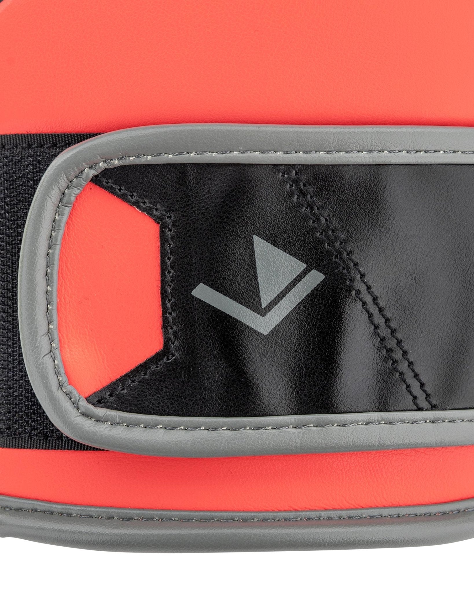 Heavy bag boxing glove close-up: black wrist pad with grey stitching and V logo on red band