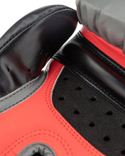 Heavy bag boxing glove close-up: black leather, red curved panel, and vent holes on palm
