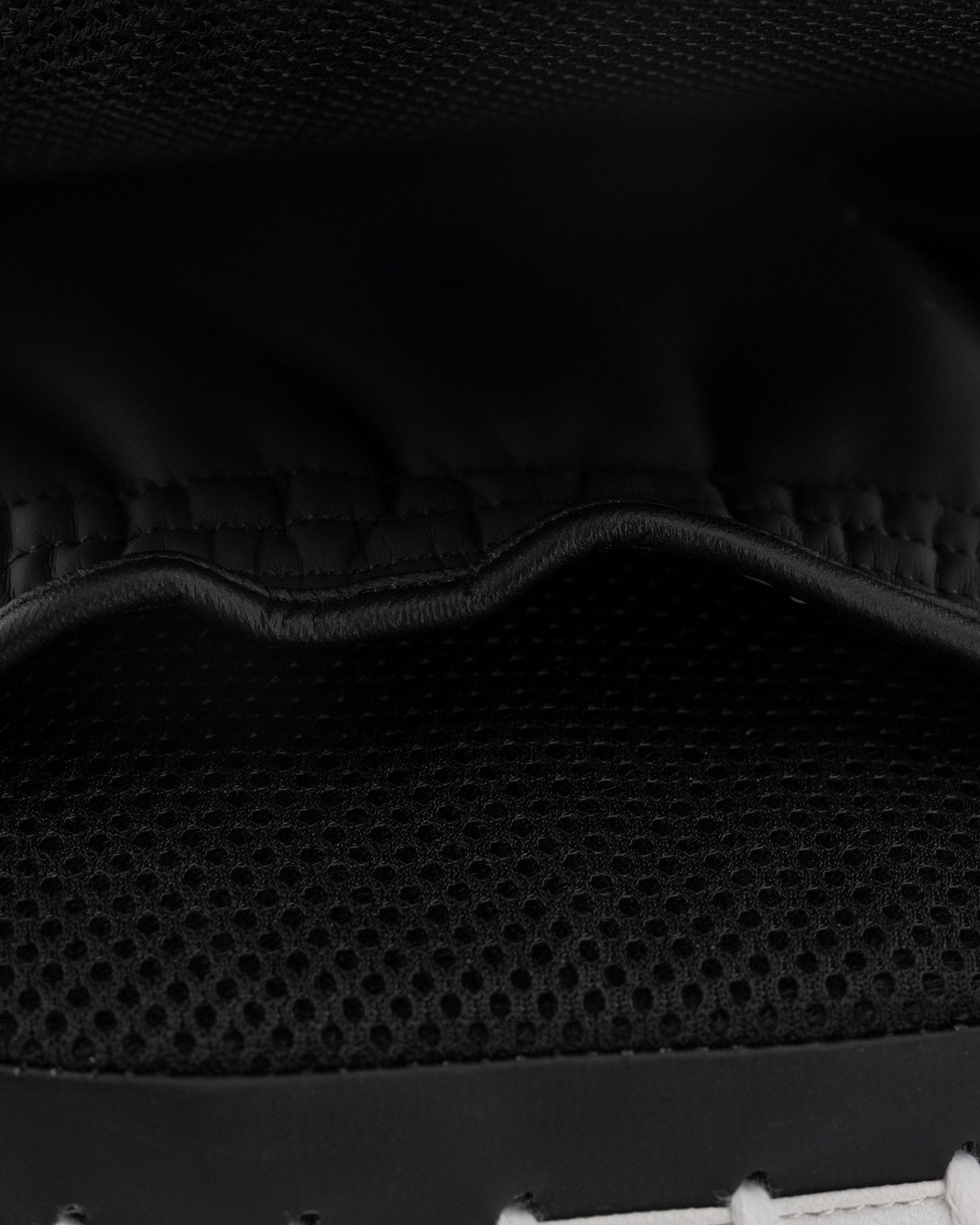 Focus mitt close-up: textured black padding with stitched seam and wavy contour.