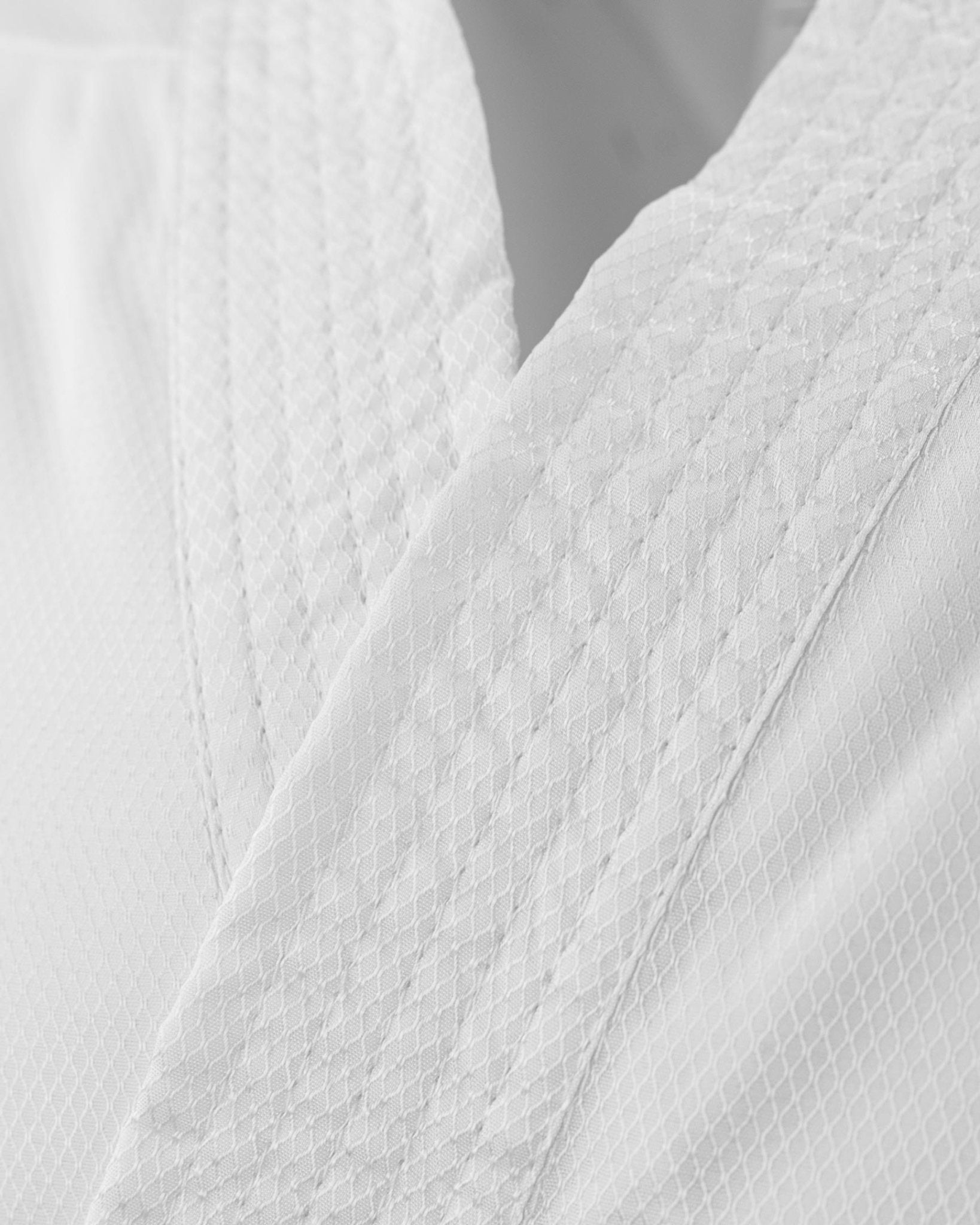 Close-up of textured white karate uniform fabric with stitched seam lines